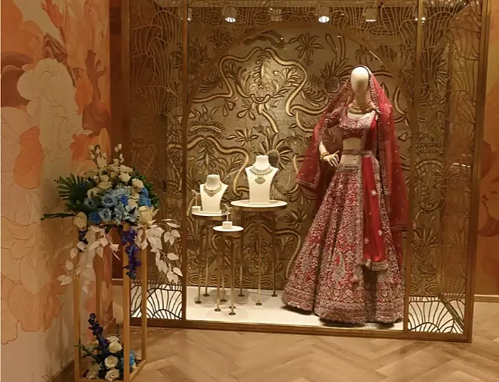 Bridal lehenga and necklace display behind a carved gold screen at Indriya Andheri West