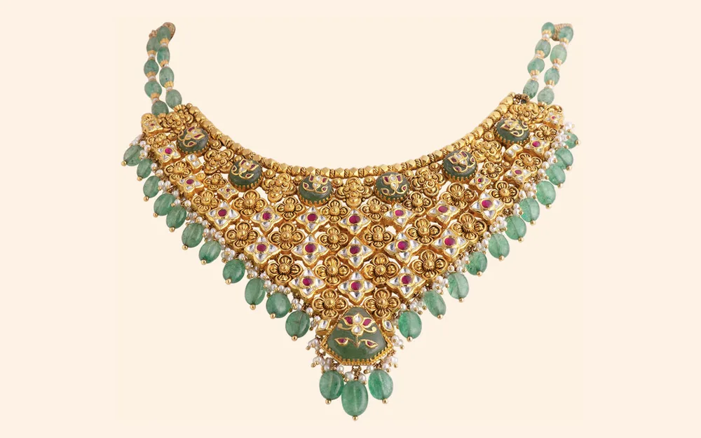 Antique gold bridal choker of gold flowers and ruby-set petals, with a lotus carved on its green centre stone and green bead drops