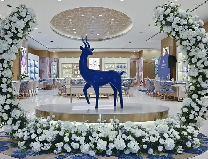 Blue deer sculpture framed by an arch of white flowers at Indriya Nexus Seawoods