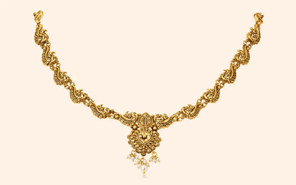 Antique gold temple necklace made of linked peacock motifs, with a carved centre pendant and pearl drops