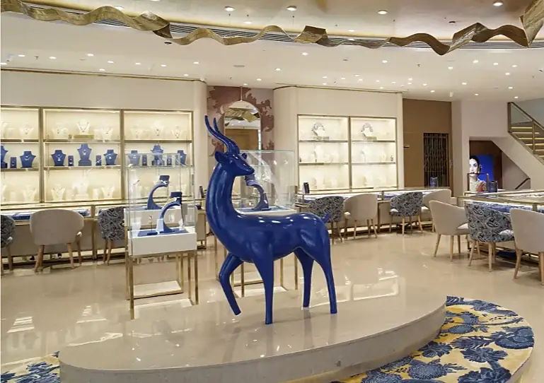 Blue deer sculpture beside lit display shelves at Indriya Sky City Mall